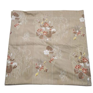 May include: A tan cushion cover with a floral design. The pattern includes clusters of brown, red, and white flowers with green stems and leaves. Vertical white stripes are visible in the background.