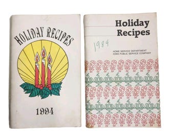 May include: Two vintage holiday recipe books. The first book cover has the text "Holiday Recipes" above a yellow circle with three red candles and the year "1994". The second book cover has the text "Holiday Recipes" and the year "1984".