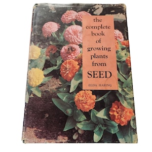 Puede incluir: Portada de libro antiguo titulada "The Complete Book of Growing Plants from Seed" de Elda Haring. La portada presenta una fotografía vibrante de zinnias coloridas en tonos rosa, naranja y amarillo, con follaje verde.