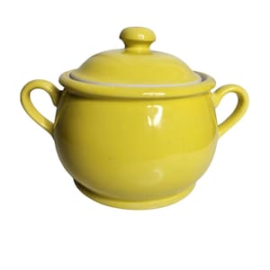 Puede incluir: Un azucarero de cerámica amarillo con tapa y dos asas. El tazón es redondo y tiene un acabado liso y brillante.