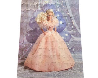 May include: A vintage Barbie doll puzzle featuring a blonde Barbie doll wearing a pink gown and a tiara. The doll is surrounded by blue balloons and a white background.