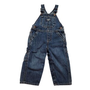 May include: Dark blue denim OshKosh B'gosh overalls. The dungarees have adjustable straps, multiple pockets, and metal hardware. The bib features a small logo patch. The garment is designed for children.