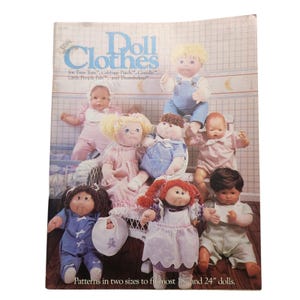 May include: A vintage doll clothes pattern book featuring various dolls in different outfits. The cover reads "Doll Clothes" and includes text for Tiny Tots, Cabbage Patch, Corolle, Little People Pals, and Thumbelina. The pattern fits 18" and 24" dolls.