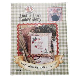 以下が含まれることがあります： Gooseberry Patchの「Fast & Fun Embroidery」というタイトルのクラフトブック。表紙はギンガムチェック柄で、「Fresh ideas for stitching fun!」と書かれたバナーがあり、刺繍された枕や花の模様が描かれています。
