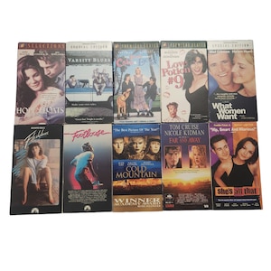 May include: A collection of ten VHS tapes featuring various movie titles, including "Varsity Blues", "Hope Floats", "Footloose", "Cold Mountain", "Love Potion #9", "What Women Want", "Far and Away", and "She's All That".