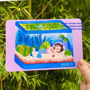 May include: A watercolor illustration of a person relaxing in an aquarium. The artwork features a blue and pink color scheme, with the word "PRICELESS" at the bottom. The image has the text "SHOP PIGEON PARADE" repeated on the top.