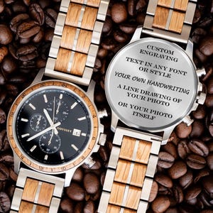 May include: A wristwatch with a black dial, silver-tone hands, and a wooden and silver-tone metal link band. The back of the watch case features the text: CUSTOM ENGRAVING, TEXT IN ANY FONT OR STYLE, YOUR OWN HANDWRITING, A LINE DRAWING OF YOUR PHOTO, OR YOUR PHOTO ITSELF.