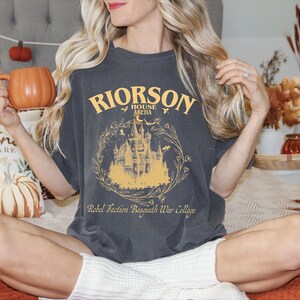 a woman sitting on a bed with a shirt on