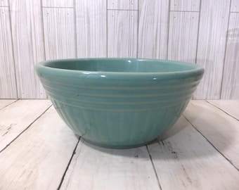 May include: A round, light teal ceramic mixing bowl featuring a series of horizontal ridges around the upper rim and vertical fluted detailing along the lower exterior body, creating a textured surface with a smooth, glossy finish throughout.