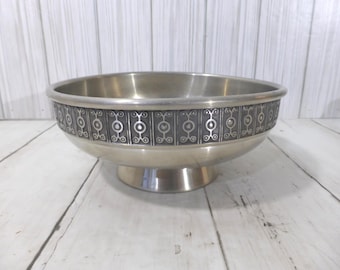 May include: A silver-toned metal bowl with a pedestal base. The exterior features a wide, dark gray band decorated with a repeating pattern of vertical lines and circular motifs. The interior of the bowl is smooth and polished with a metallic finish.