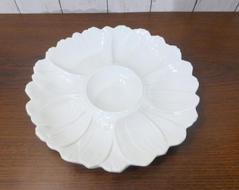 May include: A white ceramic serving platter shaped like a flower with multiple petal-shaped compartments radiating from a central circular bowl. The dish features a glossy finish and a scalloped edge, designed for organizing various food items.