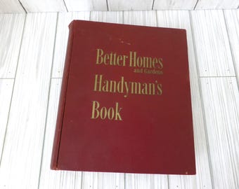 May include: A red hardcover book titled Better Homes and Gardens Handyman's Book with gold lettering on the front cover. The book is rectangular with a solid red spine and cover, featuring clear, bold text printed in a serif font on the front.