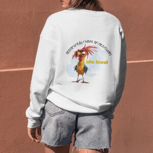 Puede incluir: Sudadera blanca con una ilustraci&oacute;n de gallo de dibujos animados y el texto "aparentemente tengo una actitud! &iquest;qui&eacute;n lo sab&iacute;a!"