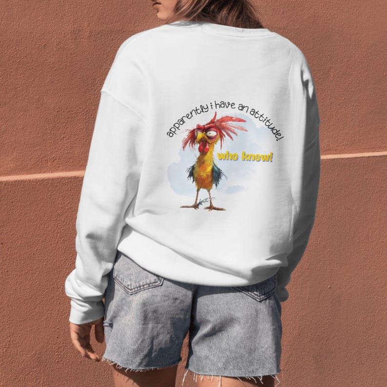 Puede incluir: Sudadera blanca con una ilustraci&oacute;n de gallo de dibujos animados y el texto "aparentemente tengo una actitud! &iquest;qui&eacute;n lo sab&iacute;a!"