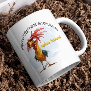 Puede incluir: Taza de caf&eacute; de cer&aacute;mica blanca con una ilustraci&oacute;n de gallo de dibujos animados y el texto "&iexcl;aparentemente tengo una actitud! &iexcl;qui&eacute;n lo sab&iacute;a!"