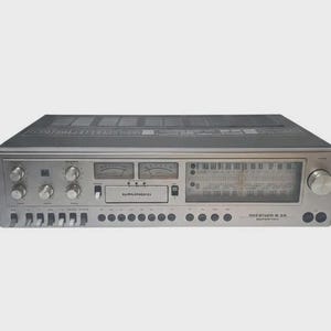 Könnte beinhalten: Silberner Vintage-Stereo-Receiver mit mehreren Knöpfen, Zifferblättern und einer Abstimmungsanzeige. Die Frontplatte hat eine gebürstete Metalloberfläche, mit dem Markennamen "Grundig" sichtbar. Eine klassische Audiokomponente.