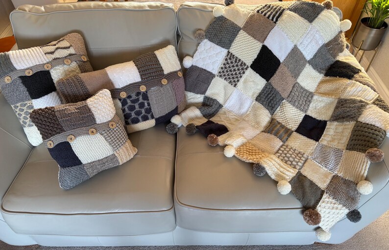 Pu&ograve; includere: Un set di cuscini e una coperta in stile patchwork nei toni neutri del grigio, crema e nero. I cuscini hanno dettagli con bottoni. La coperta, con bordi a pompon, &egrave; appoggiata su un divano chiaro.