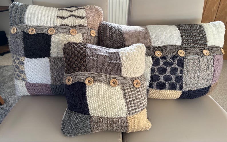 Pu&ograve; includere: Quattro cuscini decorativi con un design patchwork. Ogni cuscino presenta una variet&agrave; di trame e colori a maglia, tra cui bianco, grigio, nero e beige. Bottoni in legno adornano una fascia al centro di ogni cuscino, aggiungendo un tocco rustico.