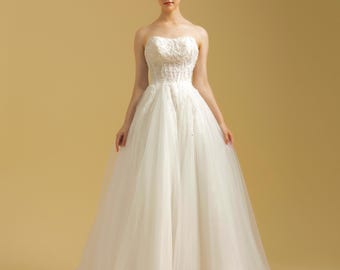 Vestido de novia de encaje sin tirantes, con corpiño de cuentas y cola catedral
