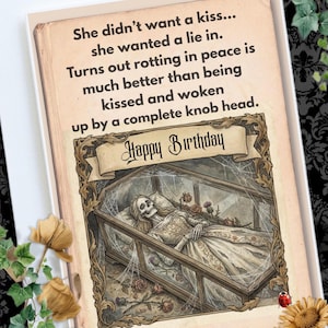 May include: A humorous birthday card with a gothic theme. The card features an illustration of a skeleton in a coffin, with the words "Happy Birthday" in a banner. The card also has a funny quote about preferring to "rot in peace".