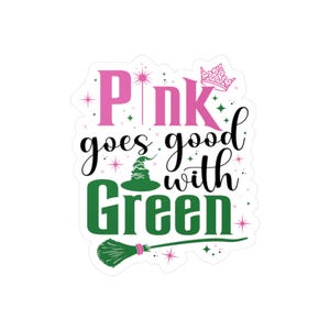 May include: A sticker with the text "Pink goes good with Green" in pink and green. The design includes a witch's hat, a crown, a magic wand, and a broom. The sticker has a white background.