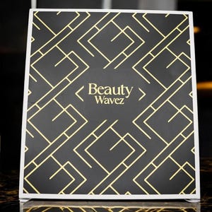 May include: A black and gold sign with a geometric pattern and the text "Beauty Wavez".