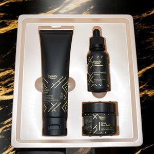 May include: A black and gold skincare set in a white box. The set includes a face wash, serum, and face butter. The products are labeled "Beauty Haven".