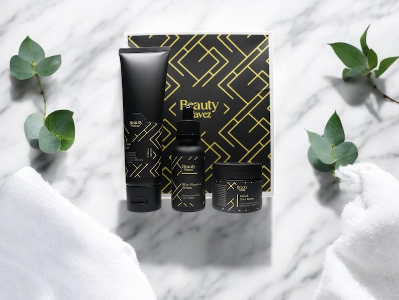 Beauty Wavez premium skincare kit with cleanser, serum, shea butter, and branded box, centered on marble with white towels and eucalyptus for elegant spa-style presentation.