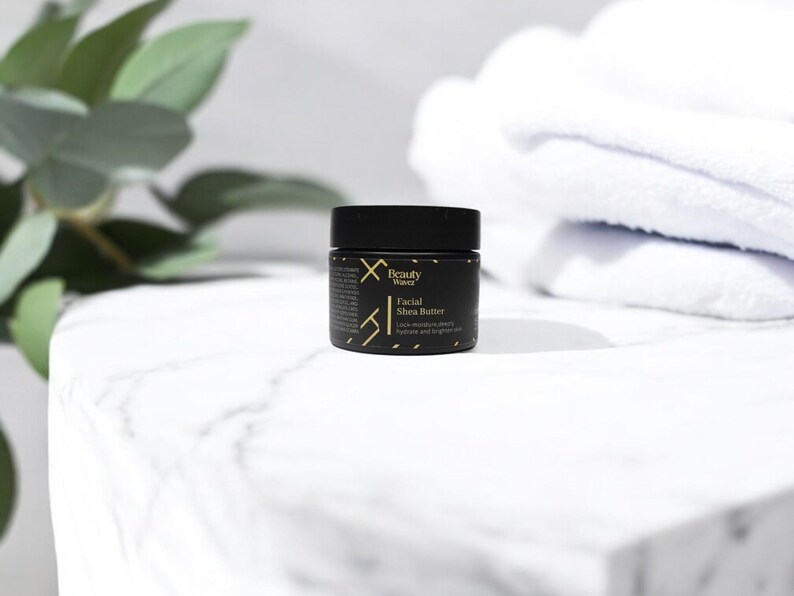 Beauty Wavez Facial Shea Butter for men displayed on a white marble edge with clean folded towels and greenery, promoting hydration and luxury self-care.