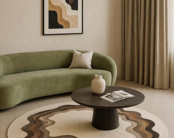 May include: A living room with a sage green curved sofa, a dark brown coffee table, and a cream rug with a brown wavy design. A framed abstract artwork hangs on the wall, and a white vase sits on the table. The rug's pattern is reminiscent of a landscape.