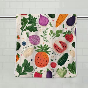 May include: White hand towel with a colorful pattern of various vegetables and fruits, including a pineapple, strawberries, and an eggplant. The text "fuck trump" is written on the towel.