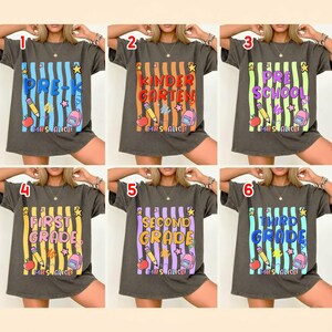 May include: A charcoal gray t-shirt featuring a graphic with vertical stripes, a pencil, an apple, a backpack, and stars. The text reads PRE-K, KINDERGARTEN, PRESCHOOL, FIRST GRADE, SECOND GRADE, or THIRD GRADE, with MRS. ALICE printed at the bottom.