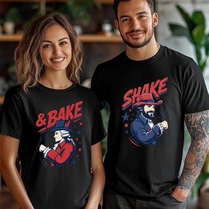 May include: Two black short-sleeved t-shirts featuring graphic prints. The left shirt displays a historical figure in a red coat with the text & BAKE. The right shirt shows a bearded figure in a blue coat and hat with the text SHAKE.