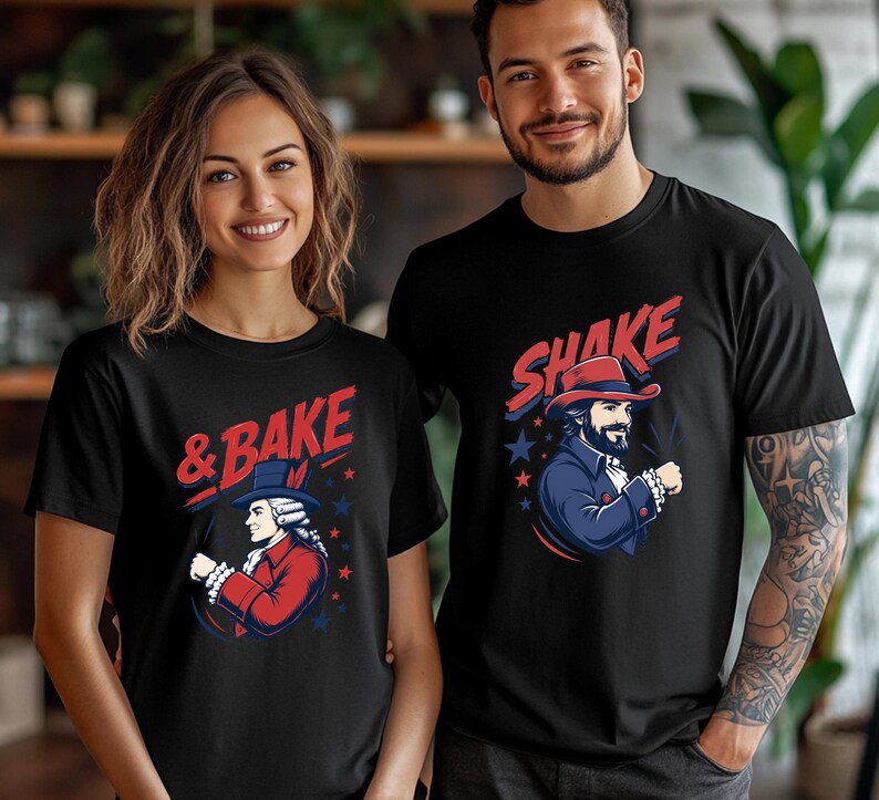 May include: Two black short-sleeved t-shirts featuring graphic prints. The left shirt displays a historical figure in a red coat with the text & BAKE. The right shirt shows a bearded figure in a blue coat and hat with the text SHAKE.