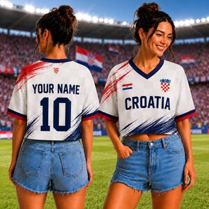 May include: A white V-neck cropped jersey featuring red and blue brushstroke accents, the text CROATIA, a small Croatian flag, and a red and white checkered crest. The back displays the text YOUR NAME and the number 10 in dark blue lettering.
