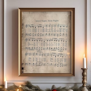 May include: A framed vintage sheet music print of the Christmas carol "Silent Night, Holy Night" with musical notes and lyrics. The print is displayed above a fireplace mantel decorated with a green garland and red and white baubles.