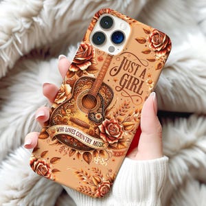 May include: A phone case with a country music theme. The case features a detailed illustration of an acoustic guitar, surrounded by roses and leaves in shades of brown and orange. Text on the case reads "Just a Girl Who Loves Country Music."