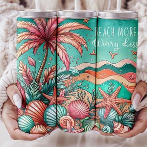 Puede incluir: Tres vasos de acero inoxidable con temática de playa. Los vasos presentan una palmera, conchas marinas, estrellas de mar y el texto "Beach More Worry Less".