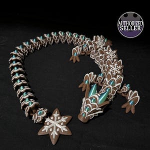 May include: A brown and white ceramic dragon figurine with a snowflake design. The dragon is curled up in a circle with its tail in its mouth. The dragon has green and blue iridescent accents.