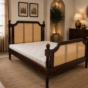 May include: A dark brown wooden bed frame featuring a tall headboard and a lower footboard, both inset with light tan woven cane panels. The bed frame has turned posts with spherical finials and holds a white tufted mattress on its base.
