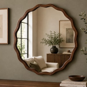 Peut inclure: Un miroir mural rond doté d'un cadre en bois brun foncé avec un bord ondulé et festonné distinct. La surface en verre réfléchissant montre l'intérieur d'une pièce avec un canapé, une armoire en bois et une plante en pot, créant un reflet clair.