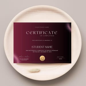 May include: A certificate of completion with a burgundy gradient background. The text reads "YOUR STUDIO NAME CERTIFICATE OF COMPLETION" and "STUDENT NAME". Includes the date and signature of Olivia Wilson.