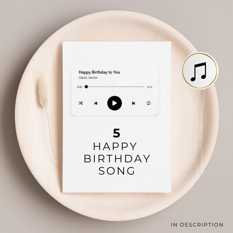 May include: A white birthday card with the text "Happy Birthday Song" and a music player graphic. The card is on a beige plate with a dried flower and a musical note icon.