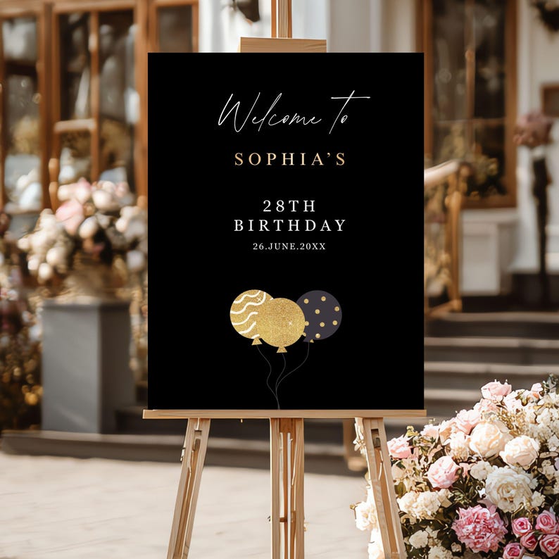 May include: A black welcome sign on a wooden easel. The sign reads "Welcome to SOPHIA'S 28TH BIRTHDAY 26.JUNE.20XX" in gold and white script. Three gold and navy blue balloons are at the bottom of the sign.