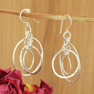 May include: Silver dangle earrings with three interlocking circles, each with a hammered texture.