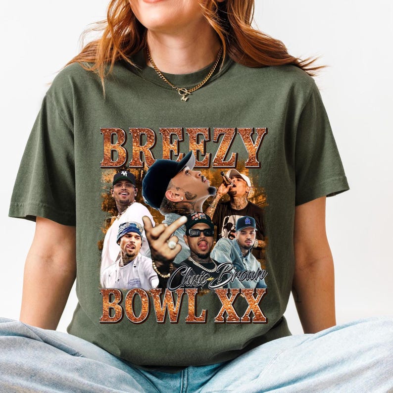 A woman wearing a green t-shirt with a graphic design featuring a group of people and the text "BREZY BOWL XX" is sitting on the floor.