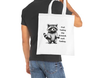 May include: White tote bag with a black and white illustration of a raccoon and the text "Not today my friend, not today." The raccoon is standing with a striped tail. The bag has white handles.