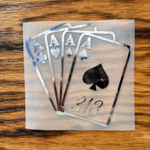 May include: Silver decal of four playing cards, each an Ace, with different suits: clubs, hearts, diamonds, and spades. The number "318" is below the cards. The decal is on a clear backing.