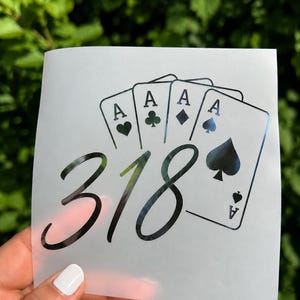 May include: A black vinyl decal on a translucent backing sheet featuring a fan of four playing cards, each showing the letter A and a suit symbol, with the number 318 written in a large, cursive script font positioned across the cards.