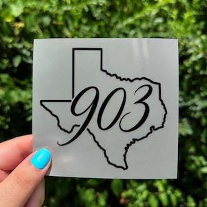 May include: A square adhesive decal featuring a black outline of the state of Texas with the number 903 written in a black cursive script font centered over the state shape, all set against a translucent matte backing material.